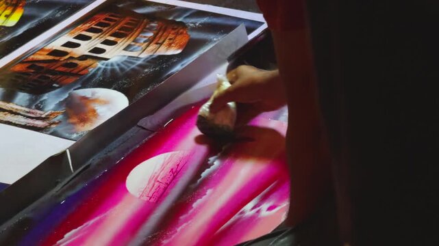 Street Artist Creating Spray Paint Art at Night Surrounded by Crowd and Displayed Prints in Rome Italy