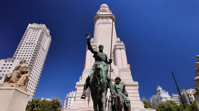 Dramatic low angle shot of the Don Quixote and Sancho Panza statues beneath the Cervantes Monument in Plaza de Espana.