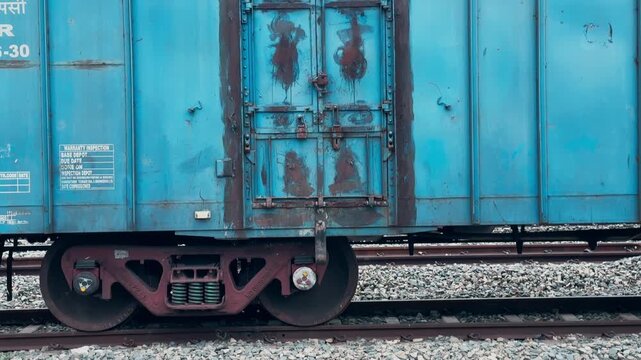 Tilt up shot showing the reinforced sliding cargo door locking mechanism and CASNUB bogie on a blue covered Indian Railways freight wagon