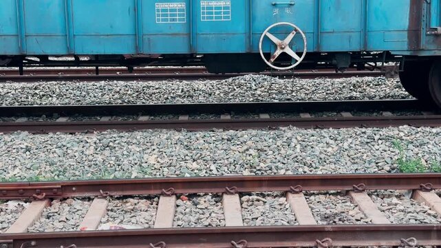 Tilt up shot from multiple railway tracks to a manual hand brake wheel mounted on a blue freight wagon