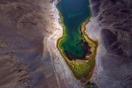 Aerial view of Borit Lake with its vibrant turquoise waters set against the rugged, arid mountain landscape of the Karakoram range in Hunza Nagar, Gilgit Baltistan, Pakistan.