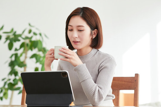 リビングでタブレットPCを見る女性