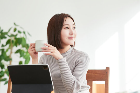 リビングでタブレットPCを見る女性