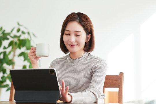 リビングでタブレットPCを見る女性