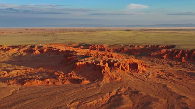 Aerial view of the red sandstone formations of the Flaming Cliffs in the Gobi Desert, with vast arid plains under a clear sky in Bulgan, Omnogovi, Mongolia.