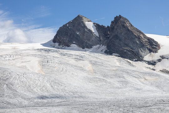 View of Ghiacciaio del Rutor, a massive glacier with rugged mountain peaks, crevasses, and snowfields under a clear blue sky in La Thuile, Aosta Valley, Italy.