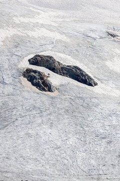 View of rocky outcrops emerging from the icy surface of the Ghiacciaio del Rutor, La Thuile, Aosta Valley, Italy.