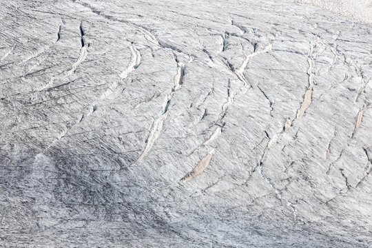 View of the Ghiacciaio del Rutor glacier surface featuring deep crevasses and textured ice formations in La Thuile, Aosta Valley, Italy.