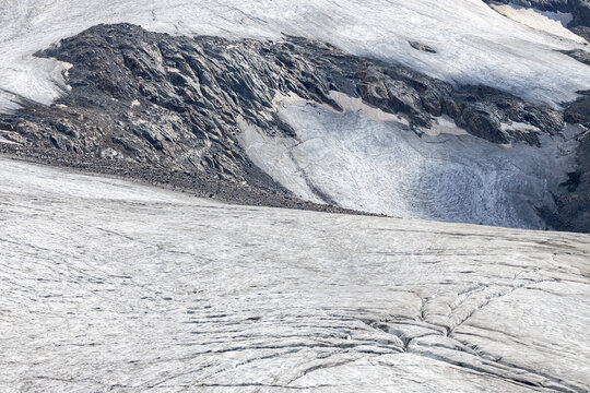 View of Ghiacciaio del Rutor showing deep crevasses, ice formations, and rocky mountain slopes in La Thuile, Aosta Valley, Italy.