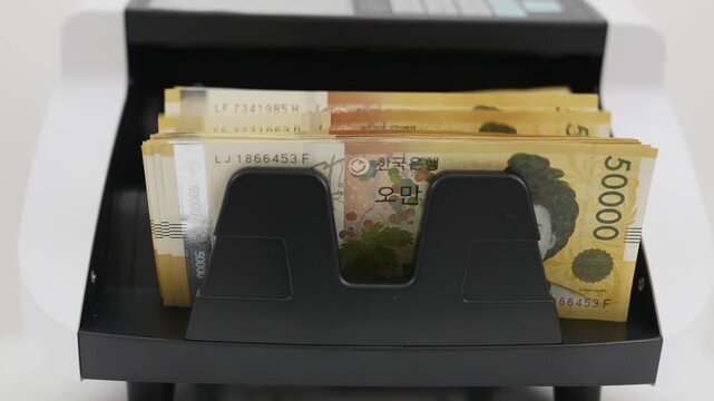 Close-up Fixed Shot of Money Counting Machine Counting 100 Crisp 50,000 Won Banknotes (Cash, Banking, Finance)