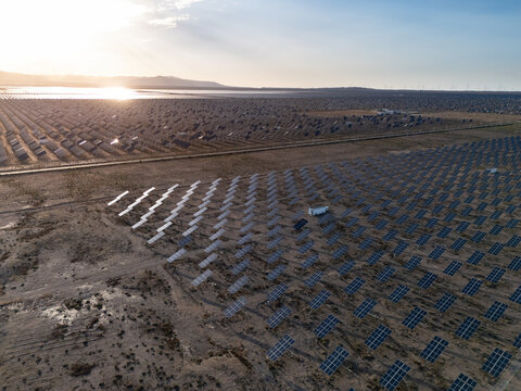 rows of solar panels in desert landscape at sunrise