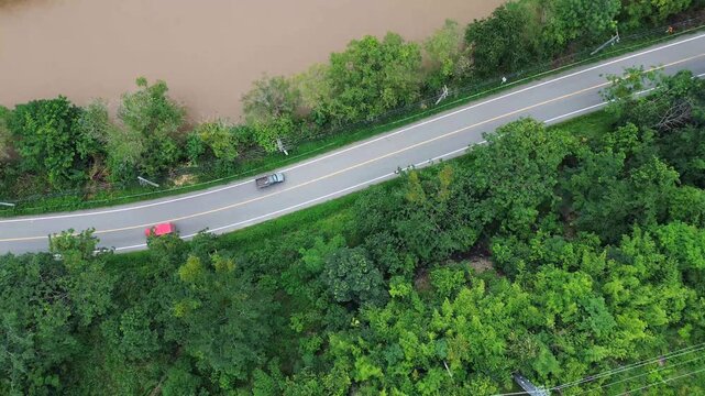 A vibrant red truck drives gracefully on a serpentine road through a lush green forest,, ESG, sustainability and green investment business concepts.