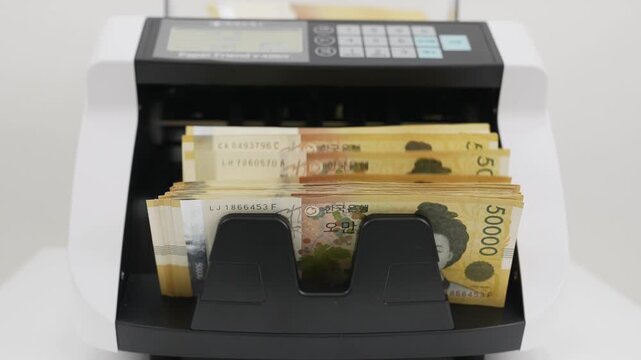 Close-up Fixed Shot of Money Counting Machine Counting 100 Crisp 50,000 Won Banknotes (Cash, Banking, Finance)