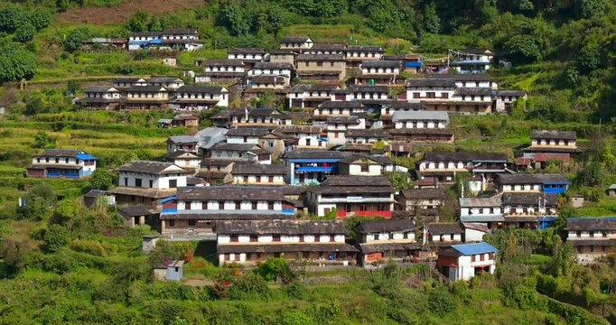Annapurna region, Nepal, Aerial shot of traditional Gurung mud and stone houses with slate roofs built along a steep green hillside near Ghandruk and Ghorepani.
