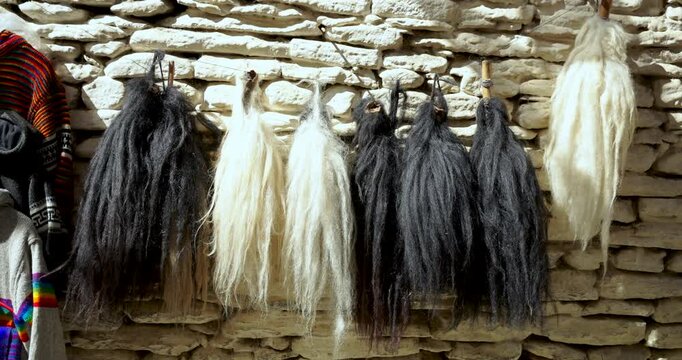 Annapurna Region, Mustang Nepal, Aerial close up shot of traditional black and white yak tail whisks (chauri) hanging against a traditional stone wall at a local Himalayan market.