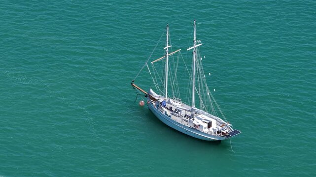 Two-masted sailing vessel floats on clear turquoise water with rigging and deck details visible
