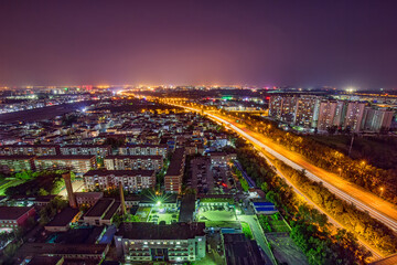 Fototapeta premium High-angle shot of a night cityscape featuring residential buildings and a busy expressway with light trails.