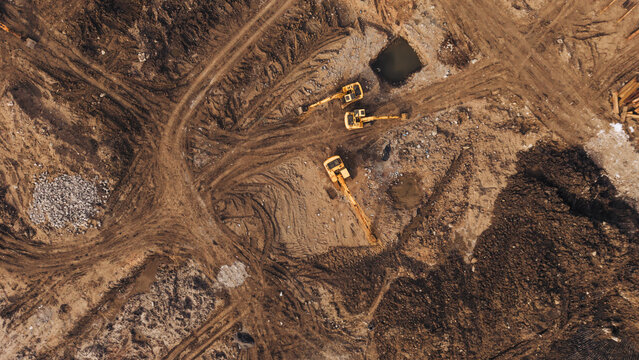Excavator on dirt access road at active construction earthworks site industrial land development