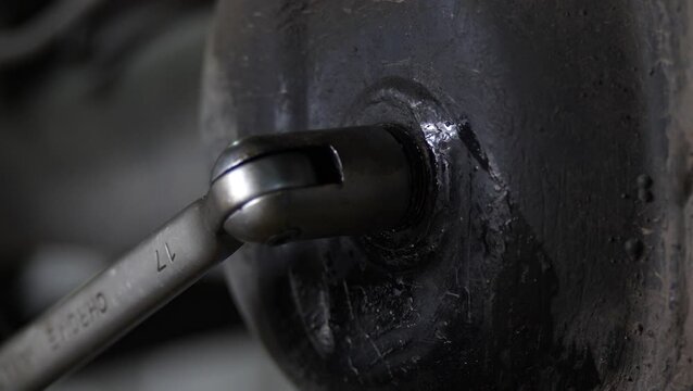 Metal wrench tightens bolt plug on a vehicle axle assembly.