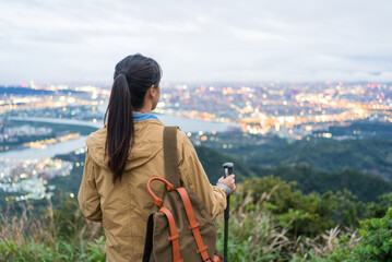 Obraz premium Rear view of hiker gazing at sprawling cityscape of Taipei from above