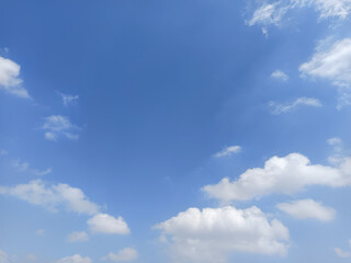 Fototapeta premium Beautiful blue sky with fluffy white cumulus clouds and delicate wispy clouds, creating a peaceful natural background with ample copy space.