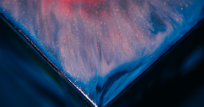 Glitter ink. Shiny fluid. Defocused blue pink color triangle marble blend sparkling texture spilling on abstract art background.