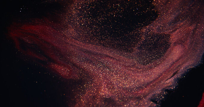Glitter paint. Fluid art. Defocused purple red color shiny blend pigment sparkling texture spilling on abstract dark background.