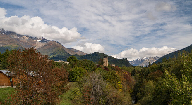 Landscape photograph of Mestia town with Svan tower surrounded by autumn trees and mountains in Svaneti Georgia.
