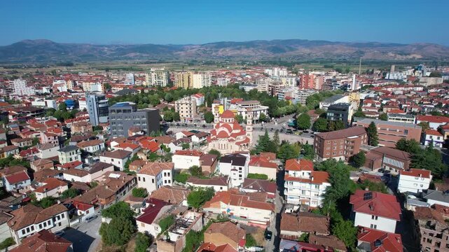 Morning sunshine on quiet pedestrian promenade in Kor&ccedil;a city center with traditional buildings and houses