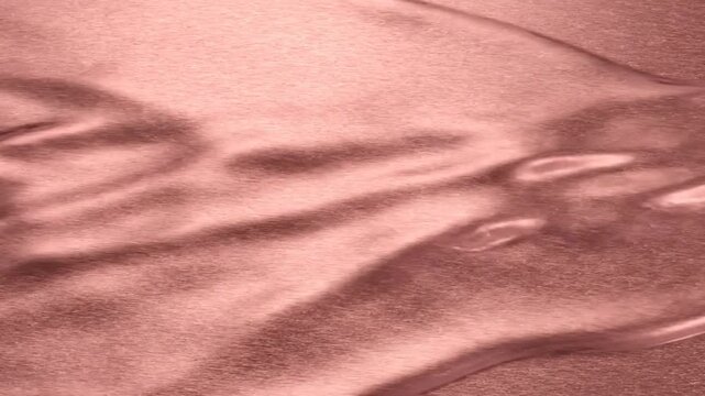 Rose Gold Liquid Metal Flowing Over a Brushed Metallic Texture Surface