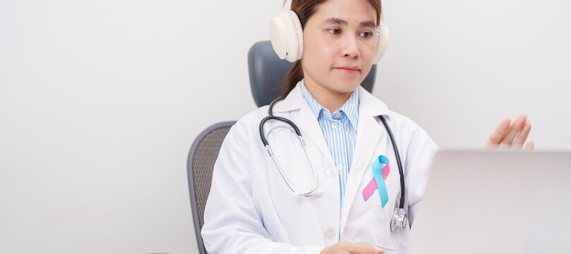 doctor using laptop for telehealth, online consultation and meeting about blue and pink ribbon concept of October male Breast Cancer Awareness month, National Cancer Survivors Month
