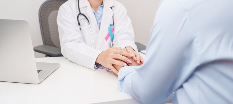 doctor hold patient hand to comfort and support with empathy. blue and pink ribbon concept of October male Breast Cancer Awareness month, National Cancer Survivors Month and Pink October Healthcare