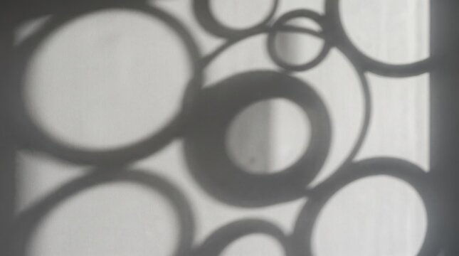 Abstract black and white photography featuring geometric circle shadows cast on a textured wall, creating a minimalist pattern of light and dark shapes, suitable for artistics
