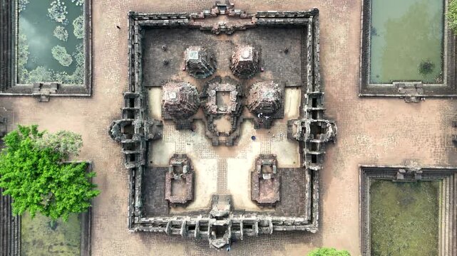 Aerial top down view of drone smoothly descending over the central towers and ancient stone ruins of Prasat Muang Tam Khmer temple