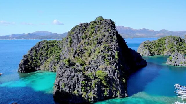 Aerial view of limestone cliffs and turquoise waters with traditional boats in Palawan, Mimaropa, Philippines.