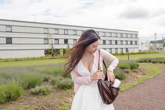 Woman open a bag while standing on sidewalk.