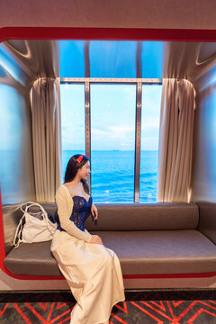 Woman relaxing on cruise ship enjoying ocean view from window.