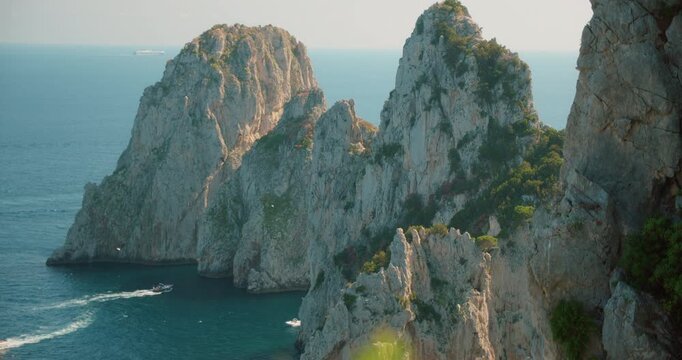 Dramatic Faraglioni rock cliffs rise from the deep blue summer sea off Capri island