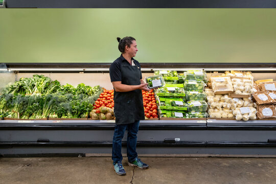 Grocery Store Owner Holding Fresh Produce in Market