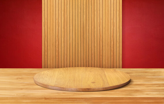 A minimalist style circular wooden stand with vertical wooden panels on a red background.
