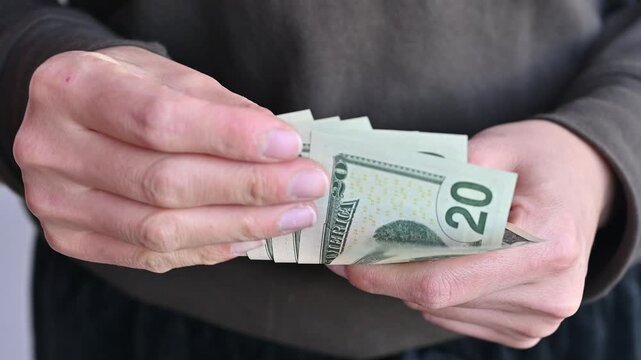 Cropped shot view of woman holding and counting Twenty American dollar banknotes in her hands. The US Dollar is the currency of United States.