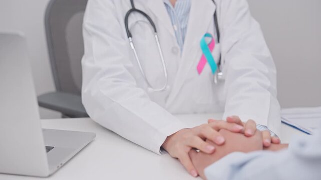 doctor hold patient hand to comfort and support with empathy. blue and pink ribbon concept of October male Breast Cancer Awareness month, National Cancer Survivors Month and Pink October Healthcare