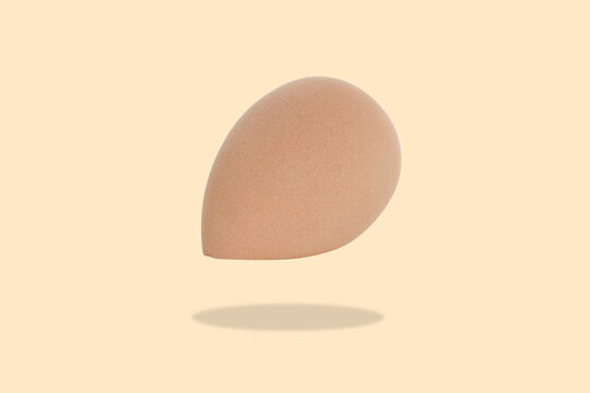 Cosmetics. Beauty sponge hovers gracefully against a pastel backdrop