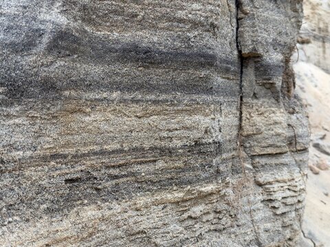 A macro texture shot displaying the intricate sedimentary layering of sand and rock on the eroding cliff side of the seaside bluffs in Carlsbad, California.
