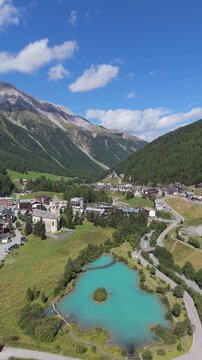 Aerial view of the turquoise alpine lake in Sulden with the historic church and village nestled in the valley surrounded by mountains in Sulden, Trentino-Alto Adige, Italy.