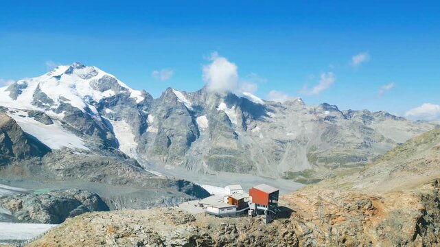 Aerial view of Diavolezza and Piz Bernina with snow-capped peaks, glaciers, and rocky terrain under a clear blue sky in Pontresina, Grisons, Switzerland.