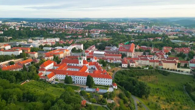 Aerial view of Strahov Monastery with its iconic red-tiled roofs and white walls surrounded by lush greenery in Hlavni mesto Praha, Hlavni mesto Praha, Czechia.