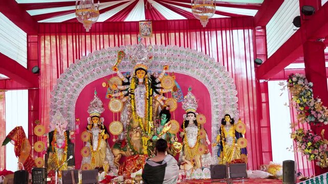 Goddess Durga Idol worshiped by blurred Hindu devotee During Durga Puja Celebration