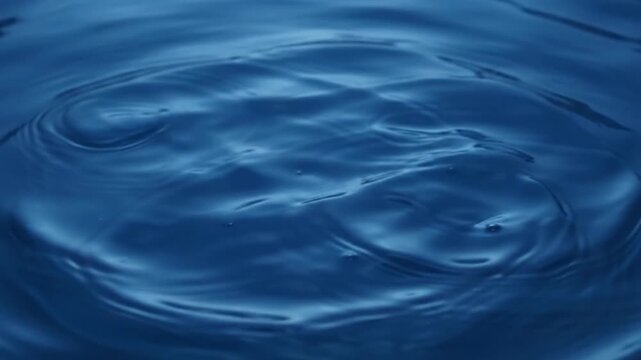 abstract blue water drop ripples expanding concentric circles liquid motion macro slow motion