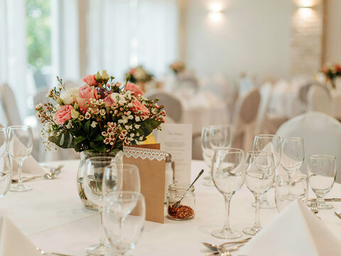 Floral arrangement in a glass vase sits on a formally set dining table indoors